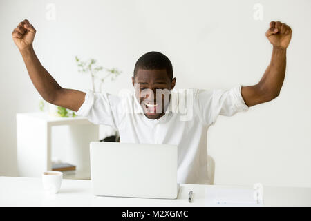 Euphorisch afrikanischen Sieger aufgeregt auf Laptop online feiert Erfolg Leistung Ergebnis gewinnen, schwarzer Mann glücklich über gute Nachrichten, durch gre motiviert Stockfoto