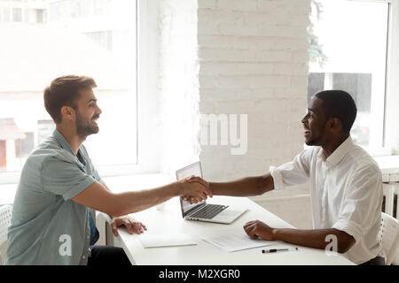 Zufrieden zufrieden afrikanische und kaukasische Partner Händeschütteln unterzeichnen Vertrag nach der Bestechung, lächelnd beschädigt diverse Geschäftsleute schließenden Viel w Stockfoto