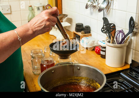 Eine Frau Abfüllung hausgemachter Marmelade. Stockfoto