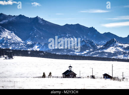 Ein kleines log Land Kirche eingebettet in einem Tal, das von hohen Rocky Mountains in Wyoming Landschaft Landschaft umgeben Stockfoto