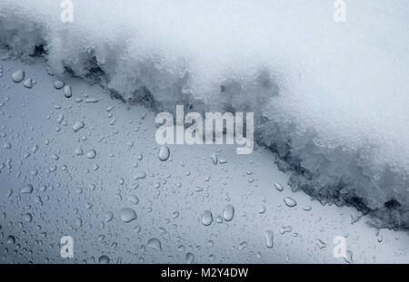 Schmelzender Schnee auf metallischen grauen Kraftfahrzeug Stockfoto