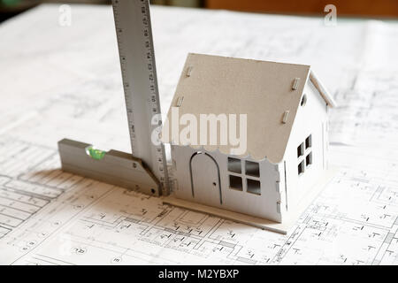 Bild des kleinen weißen Spielzeug Modell Haus auf den Architekturentwurf Plan mit einem Lineal. Architekten arbeiten Konzept Stockfoto