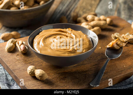 Süße Organic Natural Creamy Peanut Butter in eine Schüssel geben. Stockfoto