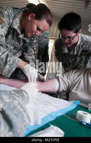 Sgt. Rebecca Leiker (RECHTS), ein Arzt mit Oklahoma Medical Loslösung, Oklahoma Army National Guard und ein Bewohner von Kansas City, Mo, beauftragt ein Gefährte Soldat auf Anwendung einer IV während der Ausbildung im Camp Gruber, Okla., Juni 13. Traditionell die Oklahoma medizinische Abteilung bietet medizinische Unterstützung für größere Einheiten. Für diese Schulung sind die Soldaten mit Schwerpunkt auf den Aufbau von taktischen Fähigkeiten zusammen mit Ihren medizinischen Bereitschaft Fähigkeiten verstärken. (US Army Foto von Sgt. Anthony Jones, 145 Mobile Public Affairs Loslösung) LEIKER Kansas cityMO durch Oklahoma National Guard Stockfoto