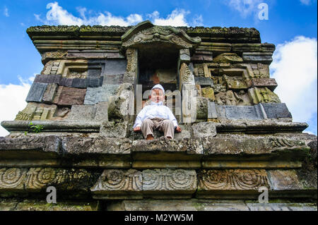 Junge Junge sitzt in einem Tempel des Arjuna Hindu Dieng Tempel Komplex, Dieng Plateau, Java, Indonesien Stockfoto