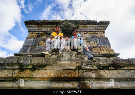 Jungen Jungen sitzen in einem Tempel des Arjuna Hindu Dieng Tempel Komplex, Dieng Plateau, Java, Indonesien Stockfoto