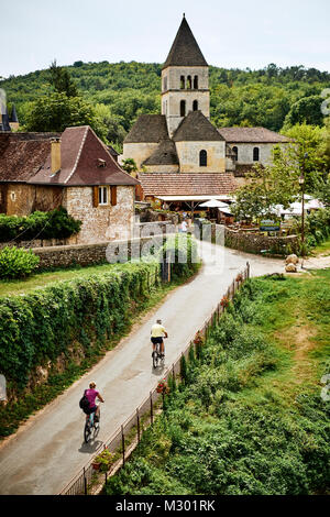 Radfahren an der Eglise Romane in St. Leon sur Vezere in der Dordogne Frankreich aufgeführt als eines der schönsten Dörfer von Frankreich Stockfoto