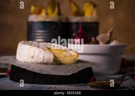 Horizontale Foto mit ganze gegrillte camambert Käse. Kleines Dreieck Stück abgeschnitten und geschmolzenem Käse ist variabel. Bratkartoffeln und Farbe onio Stockfoto