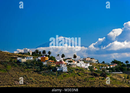 Spanien. Kanarischen Inseln. Die Insel La Gomera. Blick auf den Vulkan El Teide auf Teneriffa. Vordergrund Dorf in der Nähe von Playa de Santiago. Häuser am Hang. Stockfoto