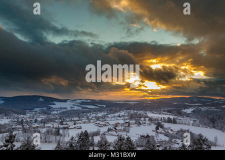 Sonnenuntergang mit dramatischen Himmel über die winterliche Landschaft in der Nähe von Neuschönau im Nationalpark Bayerischer Wald in Bayern, Deutschland. Stockfoto