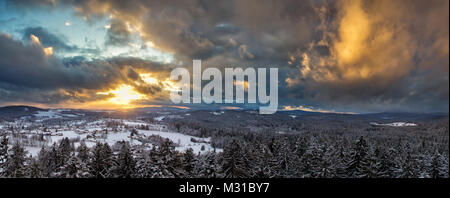 Sonnenuntergang mit dramatischen Himmel über die winterliche Landschaft in der Nähe von Neuschönau im Nationalpark Bayerischer Wald in Bayern, Deutschland. Stockfoto