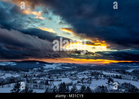 Sonnenuntergang mit dramatischen Himmel über die winterliche Landschaft in der Nähe von Neuschönau im Nationalpark Bayerischer Wald in Bayern, Deutschland. Stockfoto