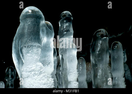 Gruppe von transparenten Eis Stalagmiten in einer Höhle Nahaufnahme auf einem dunklen Hintergrund Stockfoto