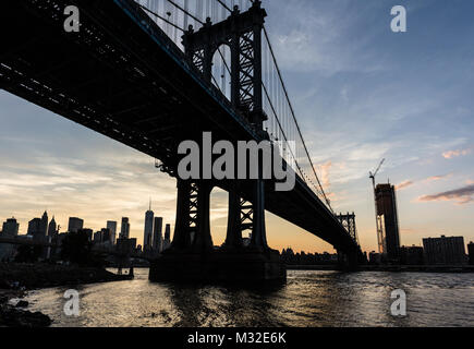 Einen atemberaubenden Sonnenuntergang über die Manhattan Bridge und Manhattan Financial District über dem East River aus Brooklyn in New York City, USA Stockfoto