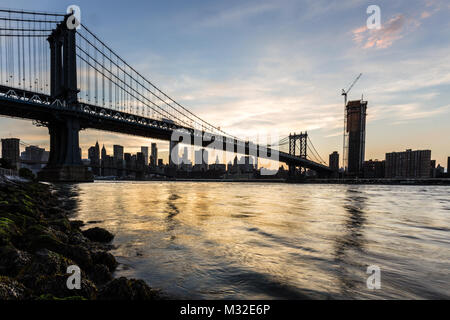 Einen atemberaubenden Sonnenuntergang über die Manhattan Bridge und Manhattan Financial District über dem East River aus Brooklyn in New York City, USA Stockfoto