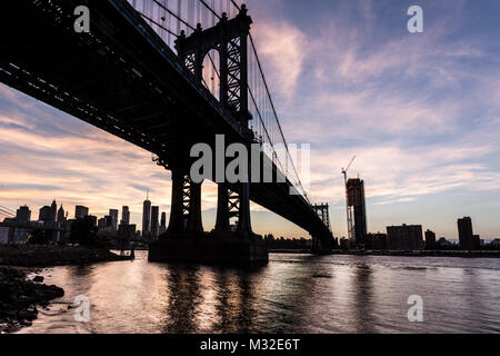 Einen atemberaubenden Sonnenuntergang über die Manhattan Bridge und Manhattan Financial District über dem East River aus Brooklyn in New York City, USA Stockfoto