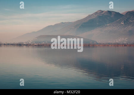 Ioannina See in der Region Epirus, Griechenland. Künstlerische Panoramablick mit natürlichen Spiegelbild im Wasser und Nebel Stockfoto