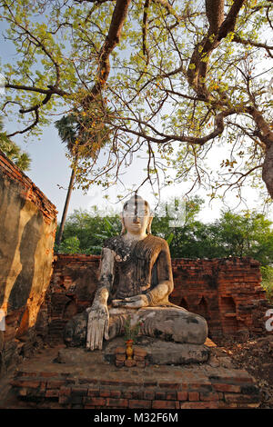 Alte Tempel Ruinen und alte Statue eines sitzenden Buddha gesehen von der Vorderseite der Yadana Hsemee Pagode Komplex in Inwa (Ava) in der Nähe von Mandalay in Myanmar. Stockfoto