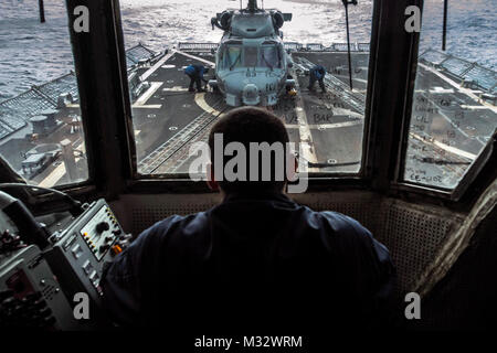 141016-N-IC 565-048 SOUTH CHINA SEA (Okt. 2010) 16, 2014), der Stern Josua Cabral, aus Rancho Santa Margarita, Calif., beobachtet von Flight Deck Control als Segler mit Unterlegkeilen sichern und die Kette ein SH-60B Seahawk Hubschrauber, von der Easyriders der Hubschrauber Maritime Strike Squadron (HSM) 37, auf dem Flugdeck der Arleigh-Burke-Klasse geführte Anti-raketen-Zerstörer USS Halsey (DDG97). Halsey ist auf den Einsatz in den USA 7 Flotte Bereich der Maßnahmen zur Förderung der Sicherheit und der Stabilität in der Indo-Asia-Pazifik-Region. (U.S. Marine Foto von Massenkommunikation Spezialisten 3. Klasse Bradley J. Gee/Freigegeben) Bewacht von #P Stockfoto