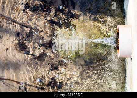 Wasser tropft aus der Regenwasserkanalisation Leitung. Abfluss von Regenwasser in den See. Saison der frühen Frühling. Stockfoto