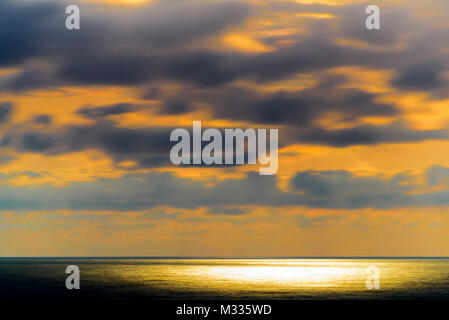 Stilisierte lange Belichtung Sonnenuntergang Meereslandschaft mit verschiedenen Schattierungen von rot, orange, gelb und blau. Stockfoto