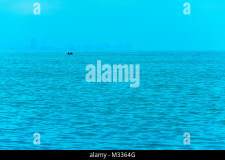 Angeln Boot im Vordergrund mit fogy Meer und die Skyline im Hintergrund. Stockfoto