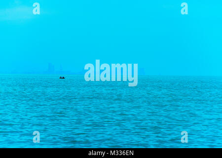 Angeln Boot im Vordergrund mit fogy Meer und die Skyline im Hintergrund. Stockfoto