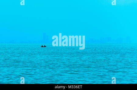 Angeln Boot im Vordergrund mit fogy Meer und die Skyline im Hintergrund. Stockfoto