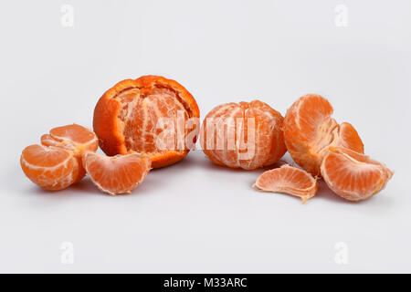 Geschälte Orangen Mandarinen und einzelnen Fruchtschnitten sind in einer Reihe auf einem weißen Hintergrund. Stockfoto