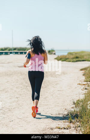 Junge Frau joggen Langlauf im Sommer am Meer. Konzept Fitness und gesunde Lebensweise Stockfoto