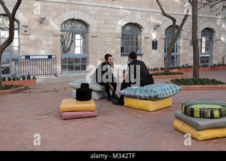 Zwei junge Orthodoxe Juden Chatten an der geformten Kissen Bereich von Designer Smadar Carmeli am Hof der Jerusalem city hall in Safra Square West Jerusalem, Israel Stockfoto