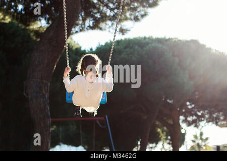 Mädchen Schwingen auf einer Schaukel auf einem Spielplatz Stockfoto