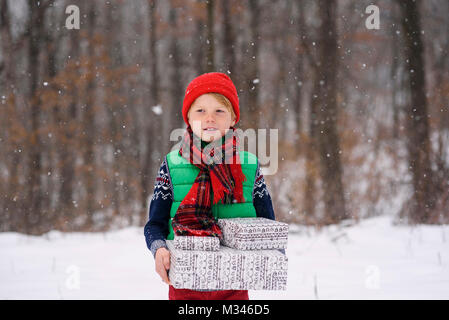 Junge im Schnee mit Weihnachten Geschenke Stockfoto