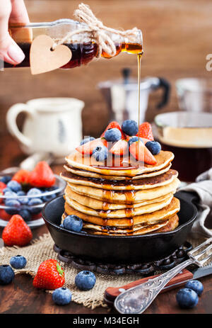 Stapel von frisch zubereiteten Banana Pancakes mit frischen Beeren und Ahornsirup zum Frühstück Stockfoto