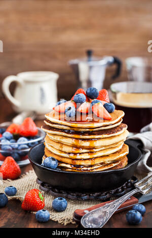 Stapel von frisch zubereiteten Banana Pancakes mit frischen Beeren und Ahornsirup zum Frühstück Stockfoto