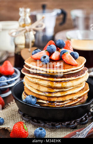 Stapel von frisch zubereiteten Banana Pancakes mit frischen Beeren und Ahornsirup zum Frühstück Stockfoto