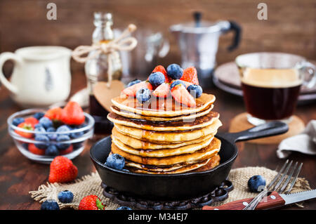 Stapel von frisch zubereiteten Banana Pancakes mit frischen Beeren und Ahornsirup zum Frühstück Stockfoto