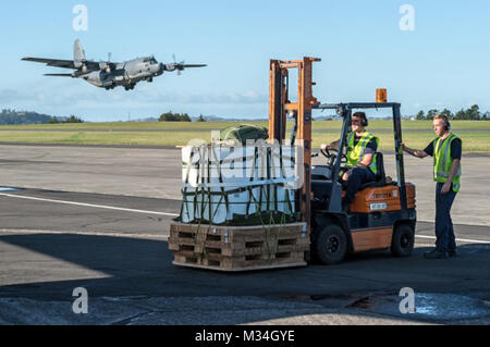 Royal New Zealand Air Force Bewegungen Personal bereiten einen Container Delivery System Palette auf einer 1 Special Operations Squadron MC-130H Combat Talon II Flugzeuge Juni 22, 2015 Whenuapai, Neuseeland, während ein anderer Combat Talon II Flugzeuge zieht im Hintergrund zu laden. Mitglieder aus der 353 Special Operations Group und der Royal New Zealand Air Force und Army beteiligt sind, die in der Übung Flash Laterne Net Juni 18-27 an der Royal New Zealand Air Force Base Auckland in Neuseeland. (New Zealand Defence Force Foto von Roderick MackenzieReleased) USA und Royal New Zealand Air Forc Stockfoto