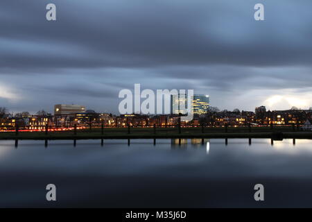 Skyline der Stadt Arnheim in den Niederlanden bei Sonnenuntergang und einem bewölkten Himmel im Januar. Lange Belichtung Bild. Stockfoto