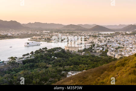 Erhöhten Blick auf den Pichola See, Aravalli Hills, und Lake Palace auf einer glühenden Sonnenuntergang Abend in Udaipur, Rajasthan, Indien. Stockfoto