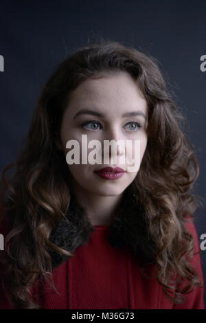 Dunkelhaarige vintage styled Mädchen im roten Mantel mit roten Lippen - auf einem sehr dunklen Grau Hintergrund isoliert Stockfoto