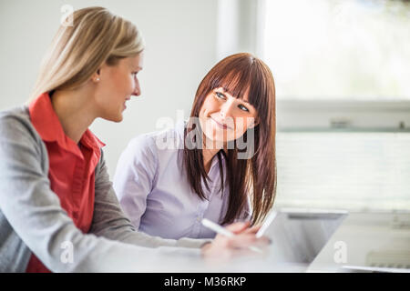 Junge Geschäftsfrau diskutiert mit Kollegin im Büro Stockfoto