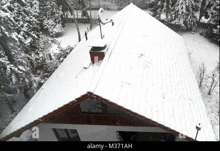 Luftbild, kleine Familie Haus in den ersten Schneefall, Schnee bedeckte Dach, Haus im Wald, drone Schuß Stockfoto