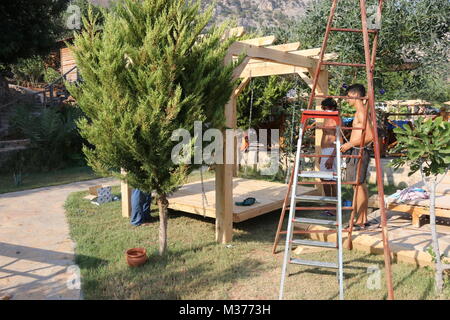 20. Juli 2017, KABAK, Türkei: Türkische Handwerker Bau einer Hollywoodschaukel Pergola in einem Olive Garden an Kabak, Türkei, 20. Juli 2017 Stockfoto