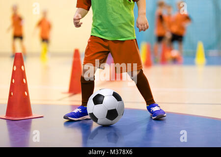 Fußball futsal Training für Kinder. Fußball-Training dribbling Konus bohren. Indoor Soccer junge Spieler mit einem Fußball in der Halle. Spieler in Stockfoto