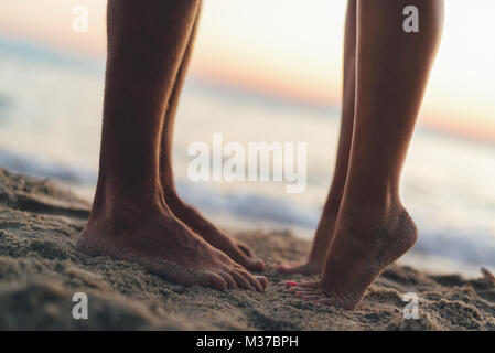 Paar umarmen und küssen am Sandstrand. In der Nähe von ein paar Füße. Stockfoto