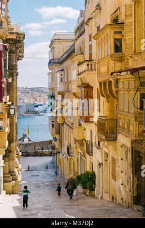 Valletta, Malta - 12. März 2017: Altstadtstraße mit traditionellen maltesischen Balkonen und faszinierendem Meerblick. Morgenstunden Stockfoto