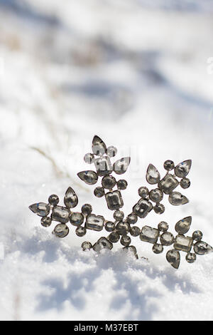 Glitzernde Schneeflocken Ornament in frischem Pulverschnee an einem sonnigen Tag. Stockfoto