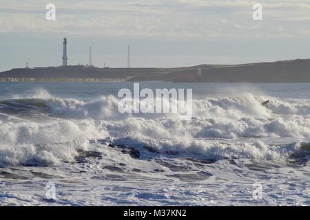 Absturz North Sea Storm Wellen bei Aberdeen Strand, Girdleness Leuchtturm im Hintergrund. Schottland, Großbritannien. Stockfoto