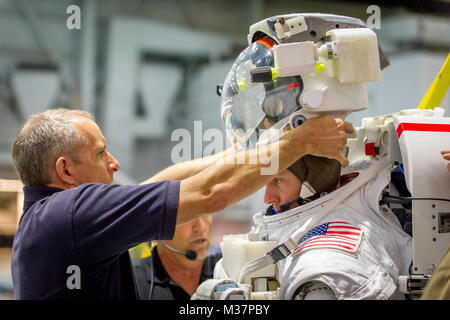 Canadian Space Agency astronaut David Saint Jacques senkt einen Helm über den Kopf der Astronaut Oberst Tyler N. 'Nick' Haag in Vorbereitung in einen Pool mit einem Modell der Internationalen Raumstation für Extra Vehicular Activity (EVA) Ausbildung bei Neutralstellung des Johnson Space Flight Center Buoyancy Laboratory in Houston, Tex, April 27, 2017 abgesenkt werden. Während NBL Ausbildung, Haag trägt einen Raumanzug im Pool, der in der Nähe von Schwerelosigkeit er Begegnung wird während der Durchführung von EVAs, oder außenbordeinsätze zu simulieren, während sie als Flugingenieur an Bord der ISS in 2018-2019. (U.S. Air Force Foto von J.M. Stockfoto